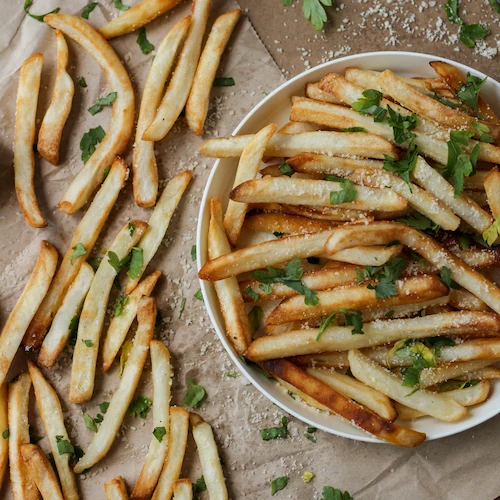 Plate of savory shoestring fries with truffle aioli, surrounded by fries and parsley garnish.